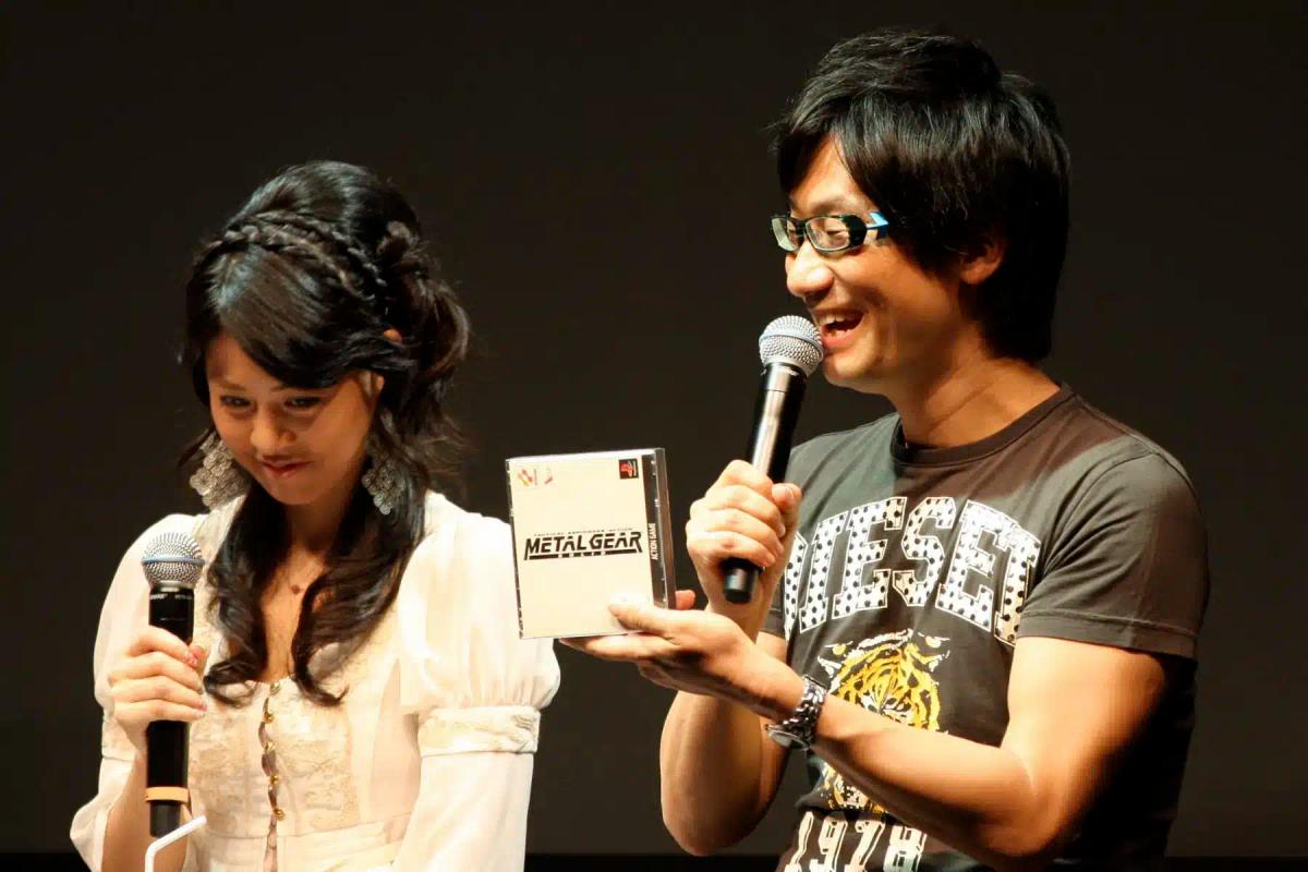 Hideo Kojima 手持《Metal Gear》游戏包装盒,正对着麦克风讲话。